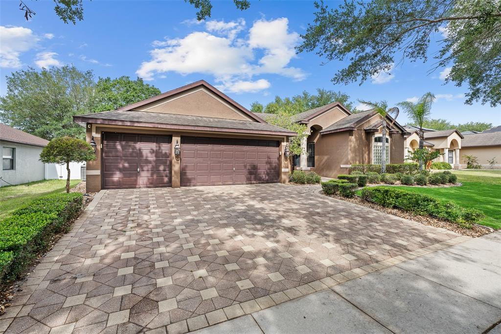 A brown house with a three-car garage and a patterned paver driveway — 1059 NATURAL OAKS DRIVE, ORANGE CITY, FL