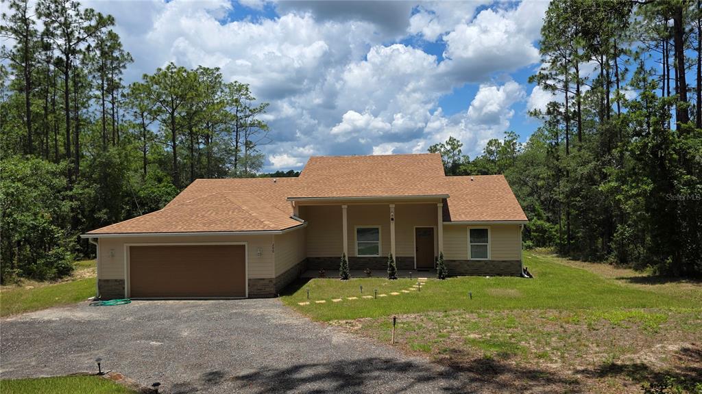 A tan, single-story house with a two-car garage and a covered front porch — 200 HOUR GLASS CIRCLE, HAWTHORNE, FL