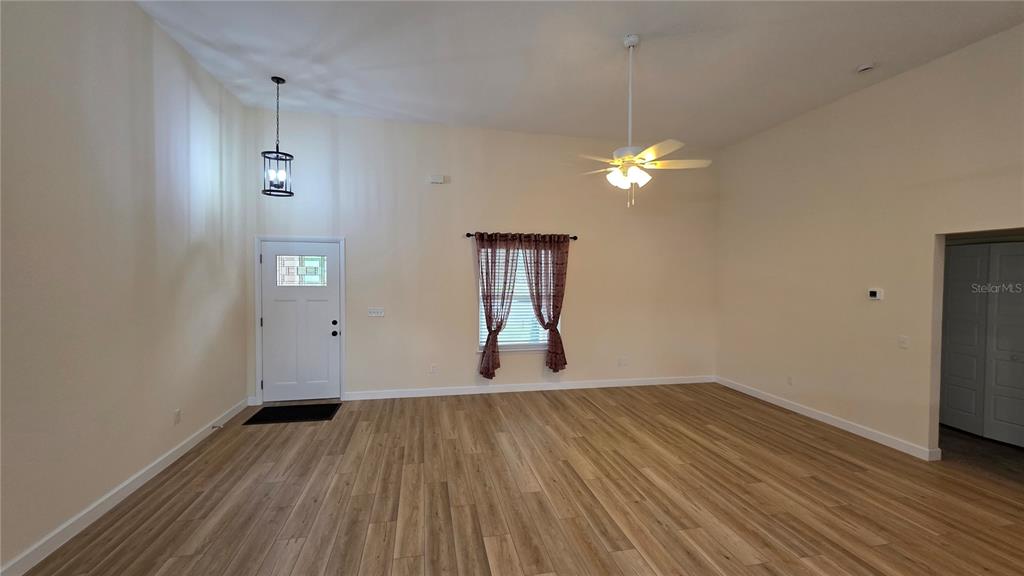 A living room with light-colored walls, wood-look flooring, a ceiling fan, and a front door — 200 HOUR GLASS CIRCLE, HAWTHORNE, FL