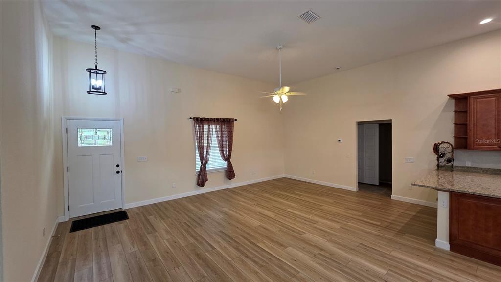 An open-concept living area features light wood flooring, a ceiling fan, and a front door — 200 HOUR GLASS CIRCLE, HAWTHORNE, FL