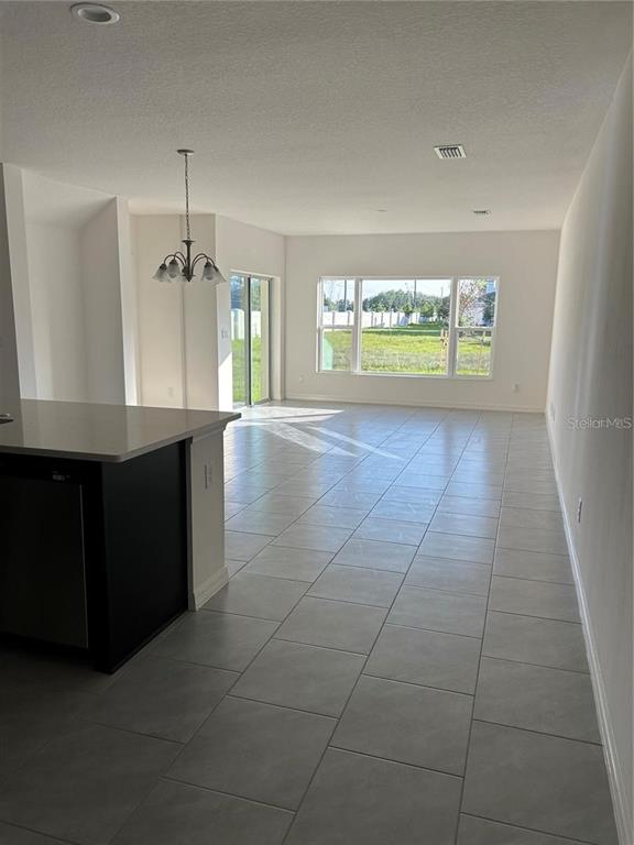 An open-concept kitchen and living area features light tile flooring and a large window — 5002 GREENBANK LANE, KISSIMMEE, FL
