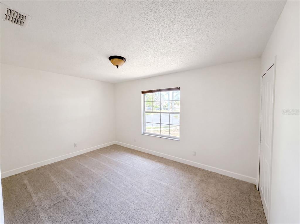 An empty bedroom with white walls, beige carpet, a single window, and a closet door — 2401 MYAKKA DRIVE, ORLANDO, FL