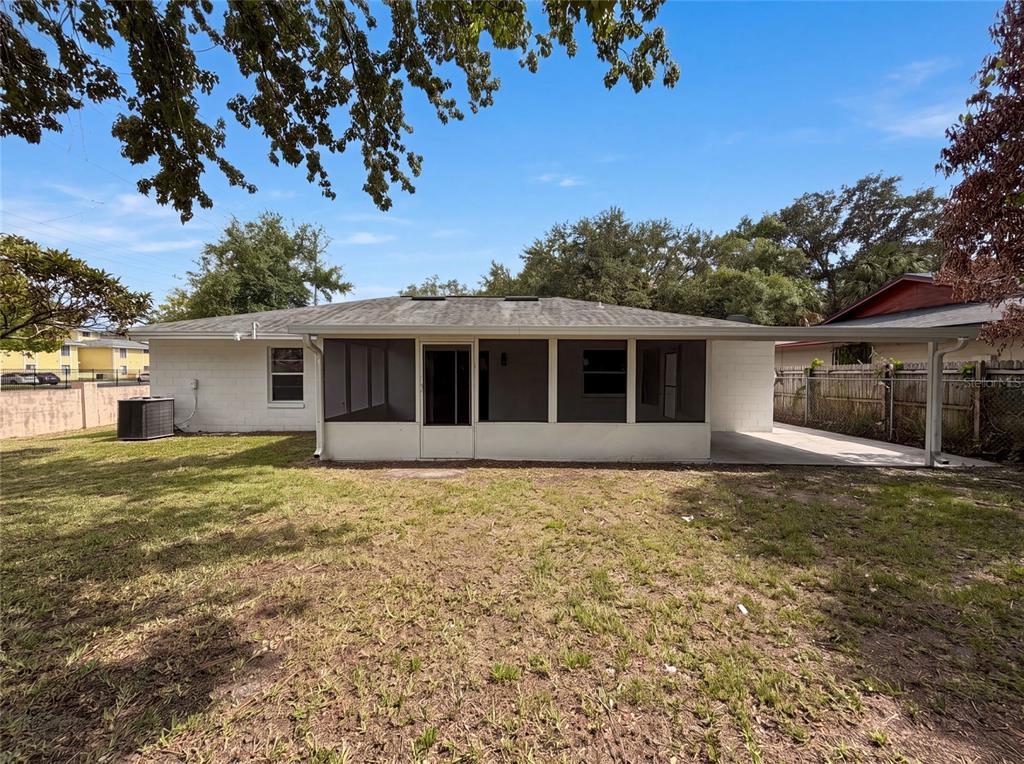 The rear exterior of a single-story house features a screened-in porch and a concrete patio — 2401 MYAKKA DRIVE, ORLANDO, FL