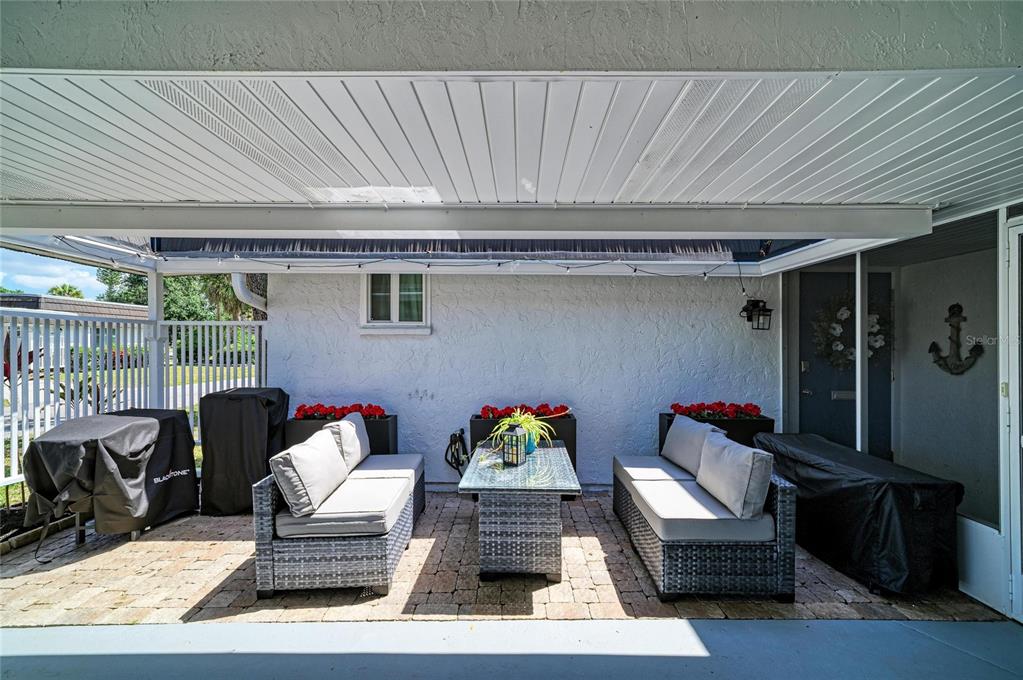 A covered patio features two wicker sofas, a glass-top table, and brick pavers — 1520 LAKESIDE WAY UNIT 147, SARASOTA, FL