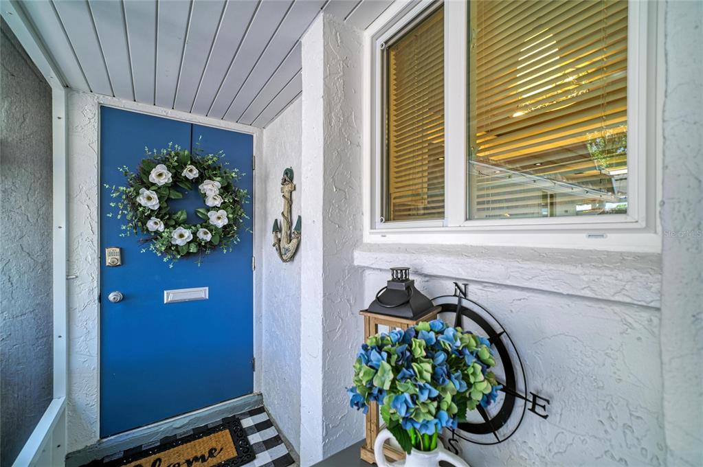 A blue front door with a wreath sits next to a window and nautical decor — 1520 LAKESIDE WAY UNIT 147, SARASOTA, FL