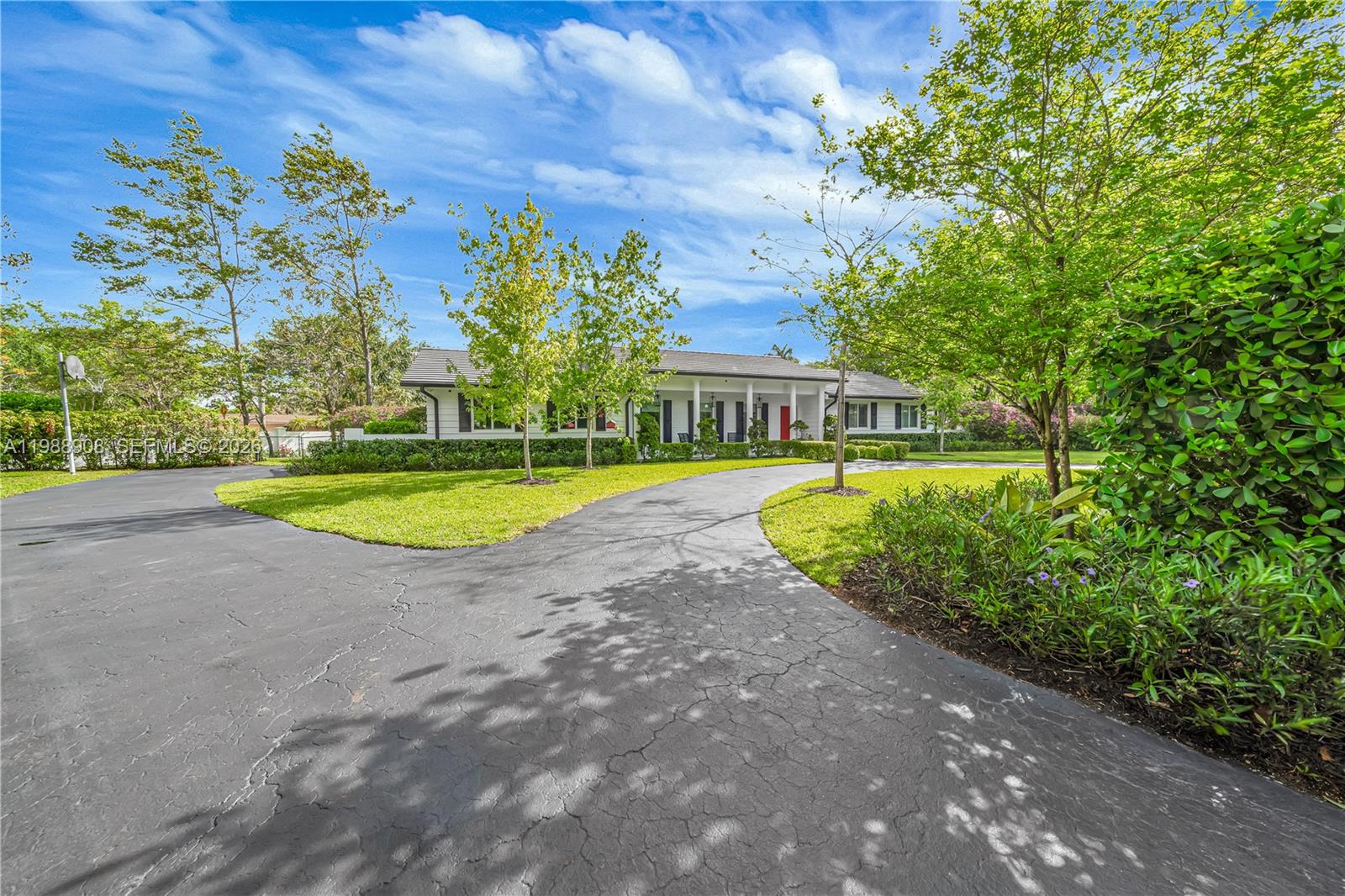 A single-story house with a white exterior and a curved asphalt driveway sits on a lawn — 10705 SW 128th Ter, Miami FL 33176, MIAMI, FL