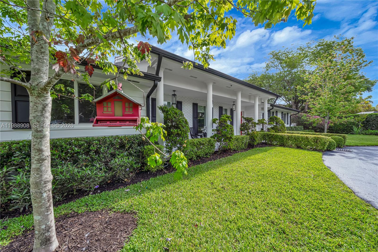 A white brick house features a covered front porch with columns and a red birdhouse — 10705 SW 128th Ter, Miami FL 33176, MIAMI, FL