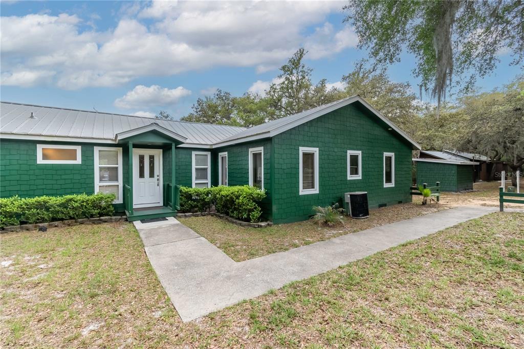 A green, shingled, single-story house with a metal roof and a concrete walkway — 22649 NE 105TH AVENUE ROAD, FORT MC COY, FL