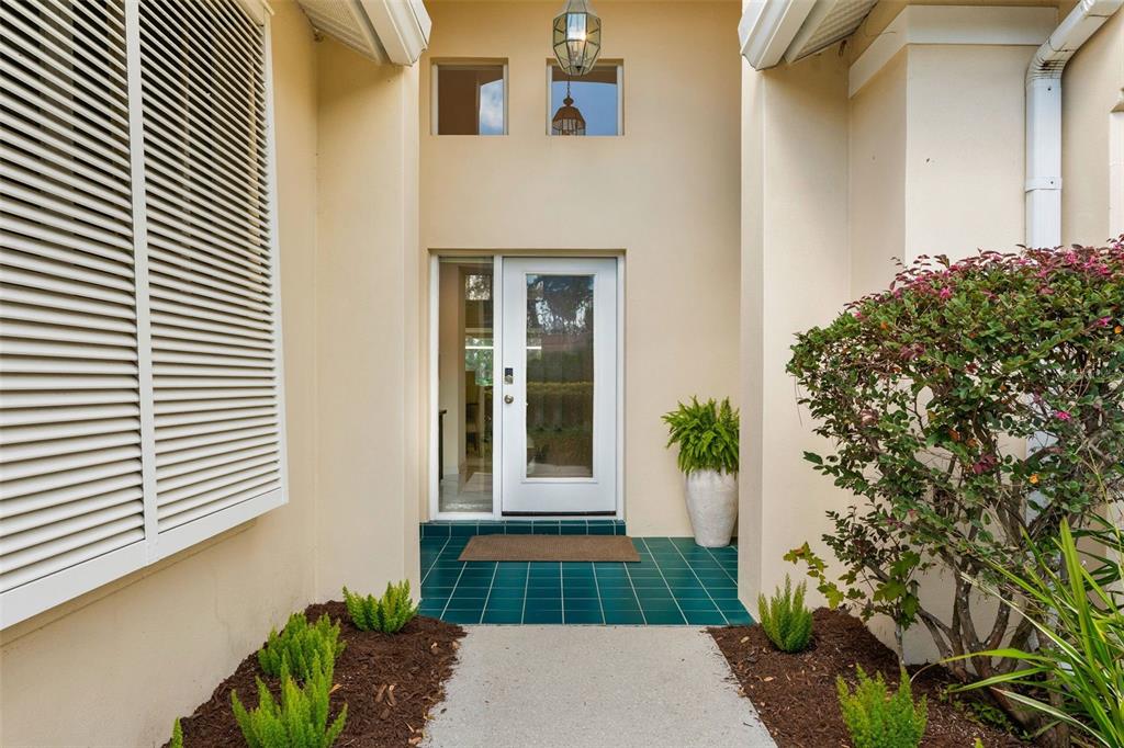 A front entryway features a white door, teal tiled porch, and a large shuttered window — 6427 BERKSHIRE PLACE, UNIVERSITY PARK, FL