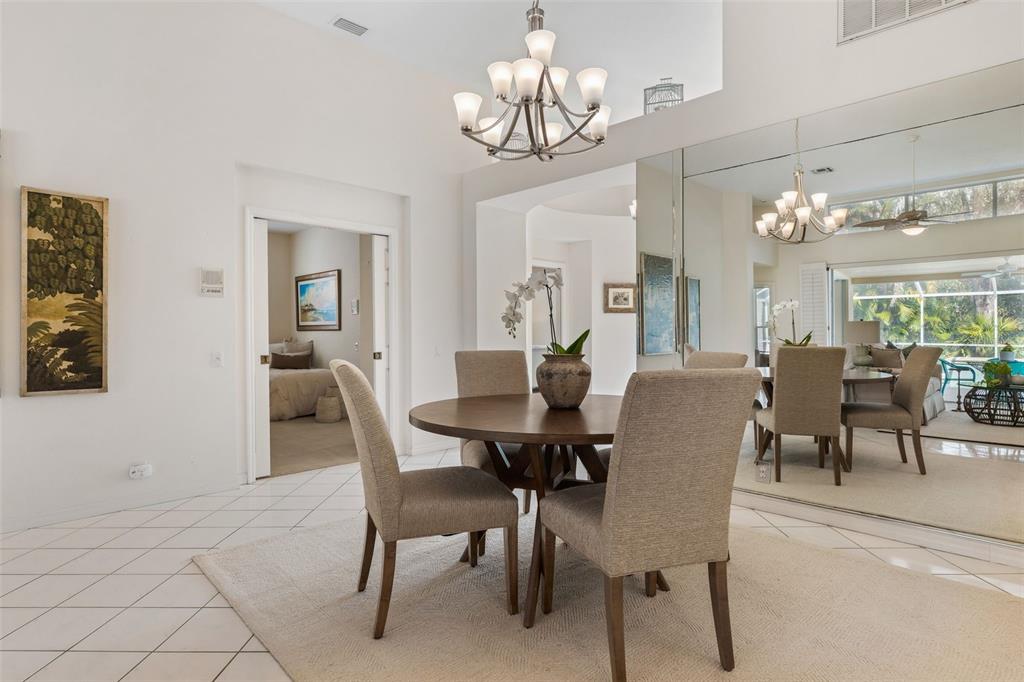 A dining area with a round table, four chairs, a chandelier, and a large wall mirror — 6427 BERKSHIRE PLACE, UNIVERSITY PARK, FL