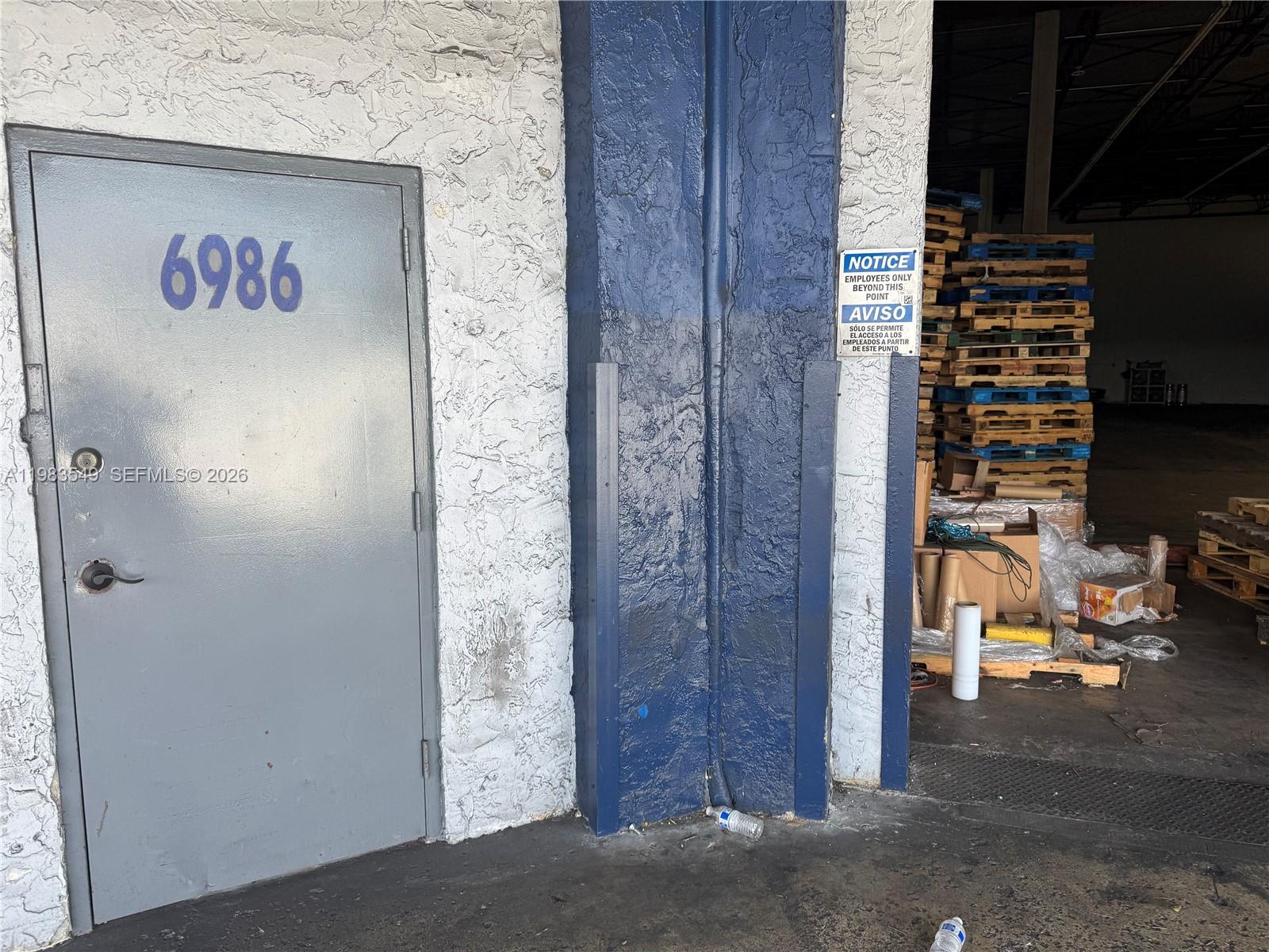 A gray door labeled 6986 stands next to a blue pillar and a warehouse loading area — 7172 NW 12th St # 6986, Miami FL 33126, MIAMI, FL