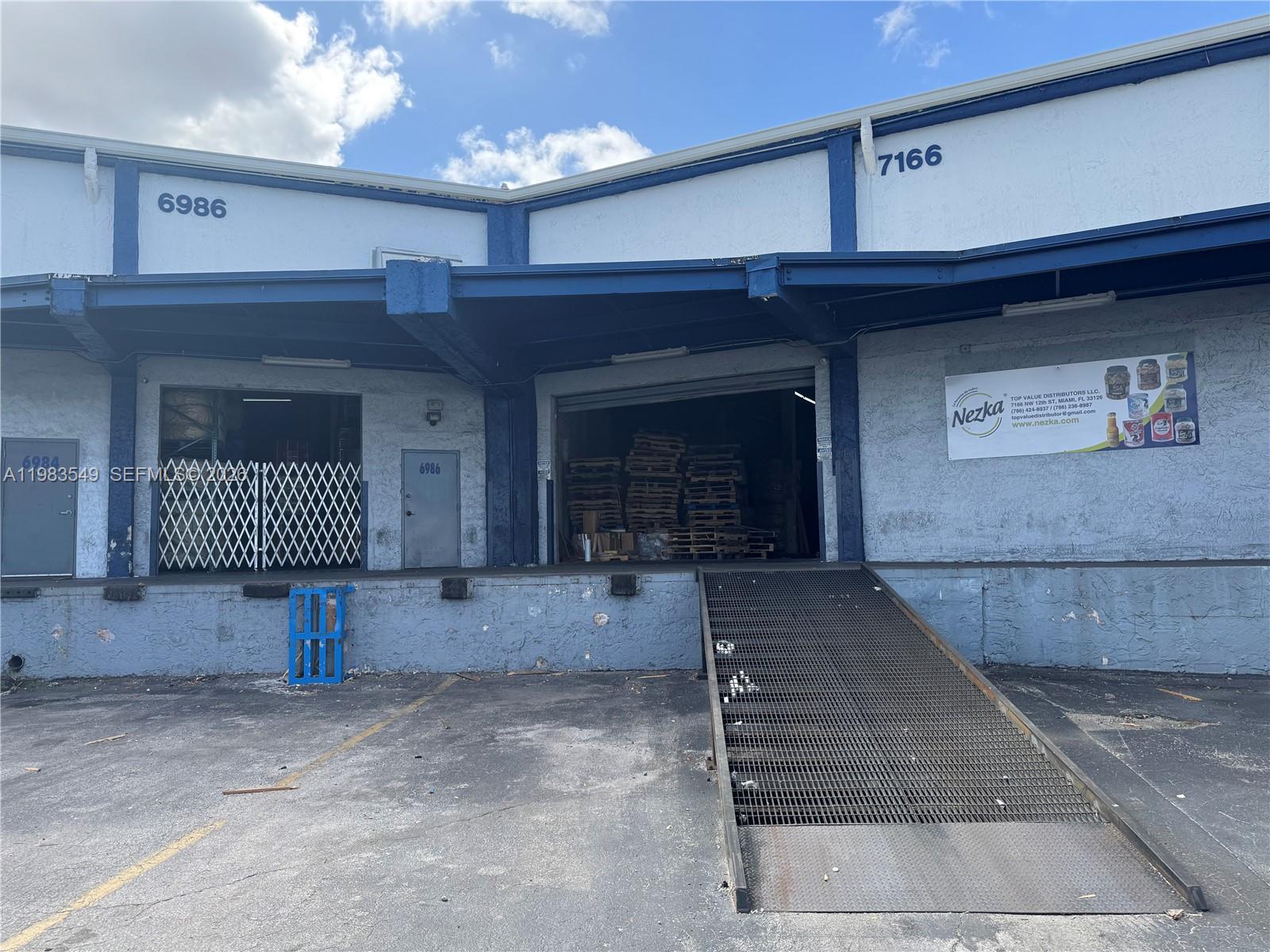 An exterior view of a commercial warehouse building with two loading docks and a metal ramp — 7172 NW 12th St # 6986, Miami FL 33126, MIAMI, FL