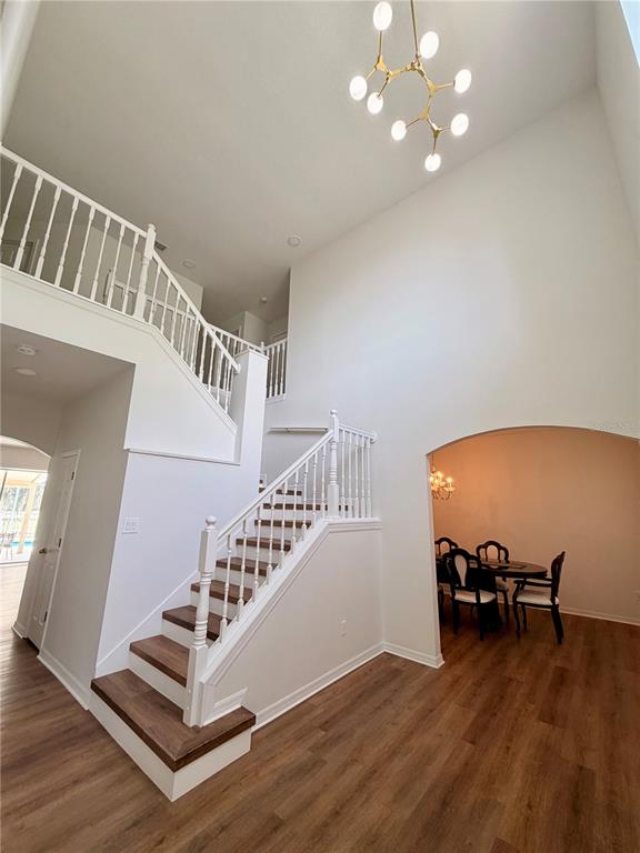 A two-story foyer features a wooden staircase, white railings, and a modern gold chandelier — 167 WESTMORELAND CIRCLE, KISSIMMEE, FL