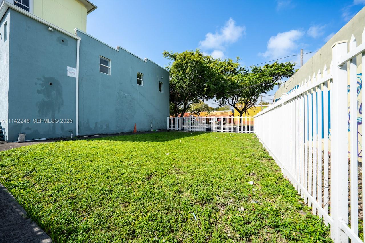 A grassy side yard sits between a blue building and a white fence — 1525 NW 3rd Ave, Miami FL 33136, MIAMI, FL