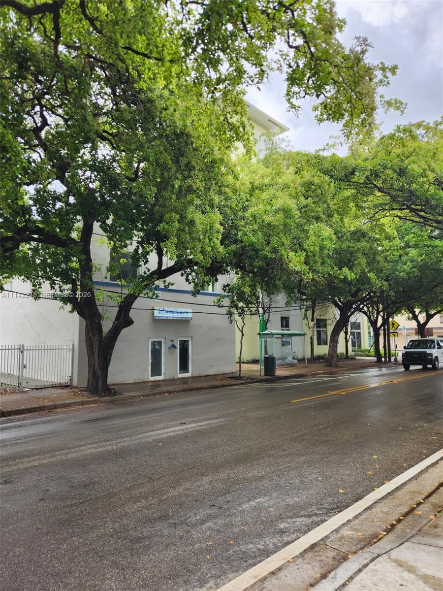 A street-level view of a commercial building with a bus stop and large trees — 1525 NW 3rd Ave, Miami FL 33136, MIAMI, FL