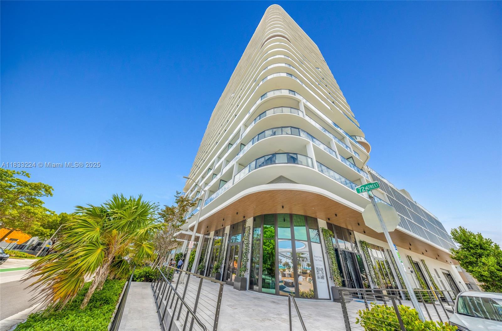 A low-angle exterior view of a modern, multi-story residential building with curved balconies — 580 72 # 910, Miami Beach FL 331441, MIAMI BEACH, FL