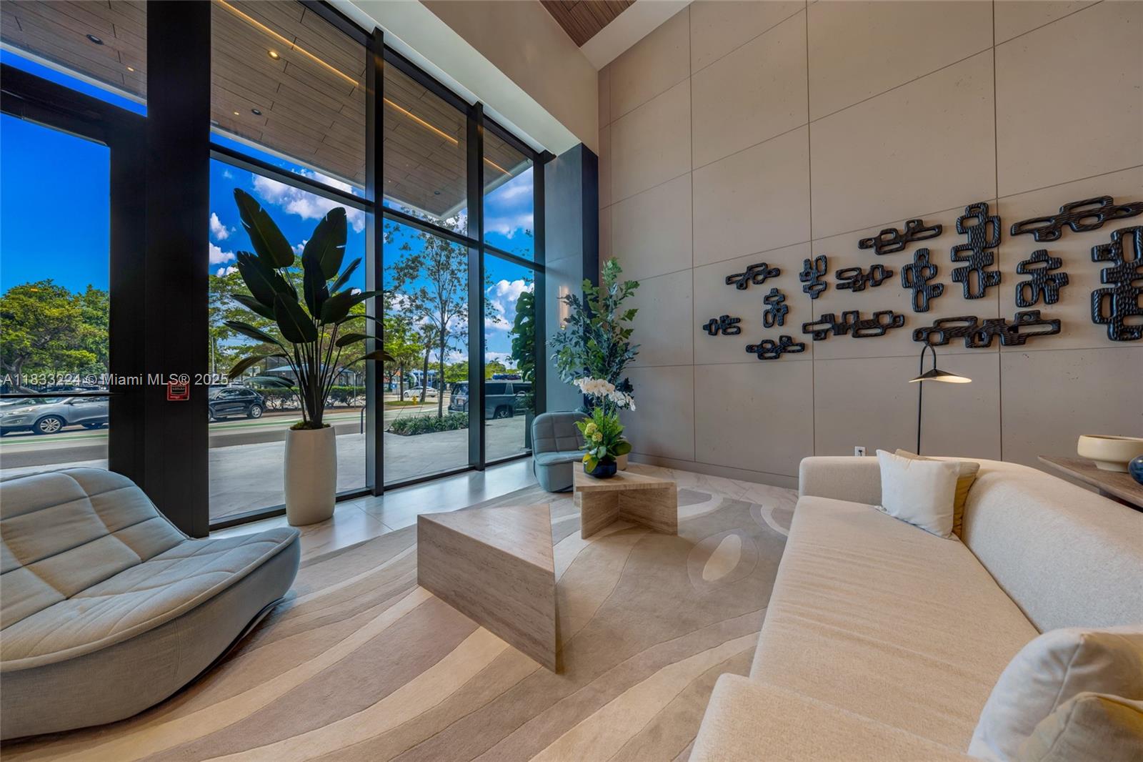 A modern lobby features floor-to-ceiling windows, a beige sofa, abstract wall art, and area rugs — 580 72 # 910, Miami Beach FL 331441, MIAMI BEACH, FL