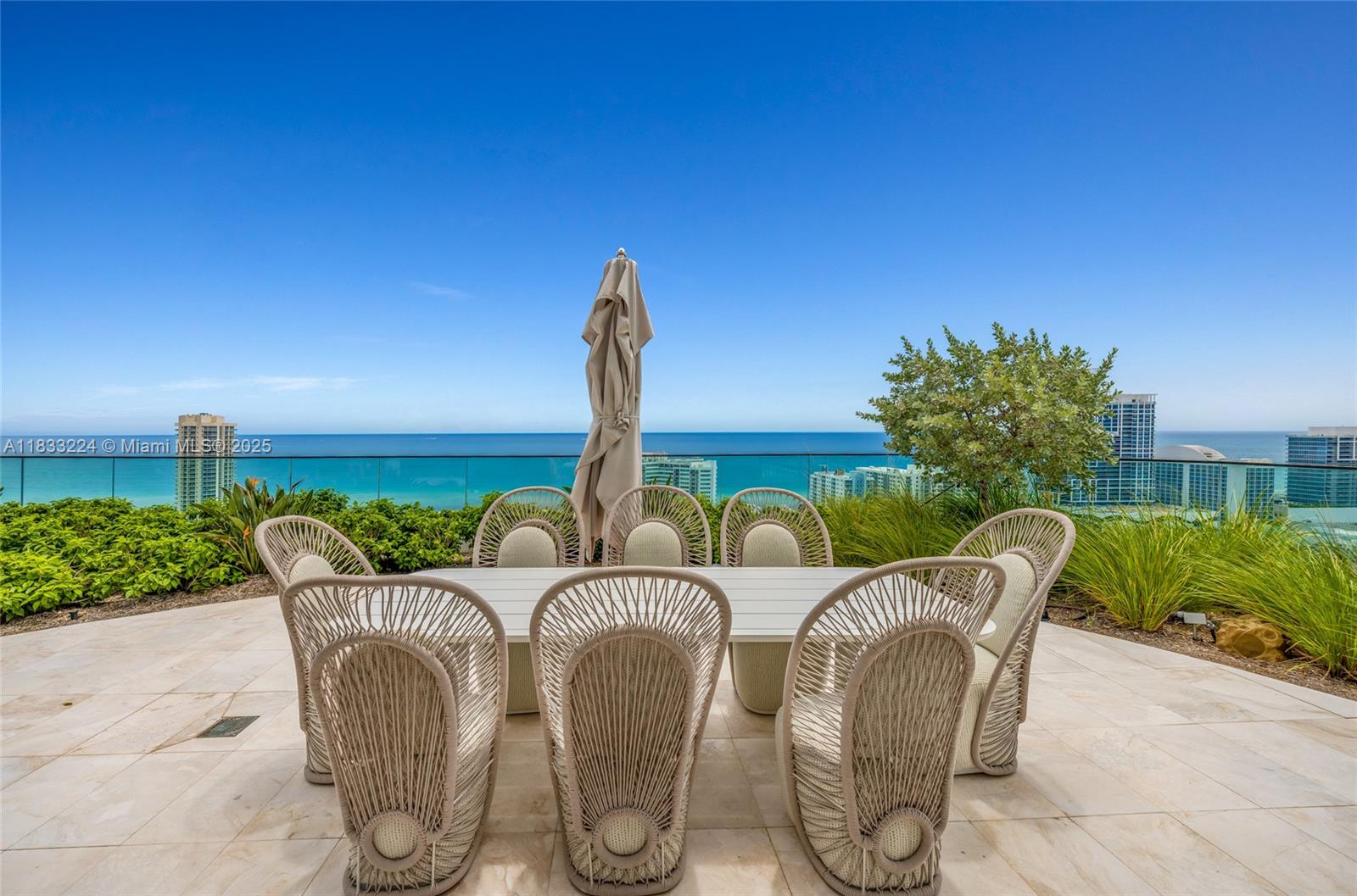 An outdoor patio features a dining set with woven chairs overlooking the ocean — 580 72 # 910, Miami Beach FL 331441, MIAMI BEACH, FL