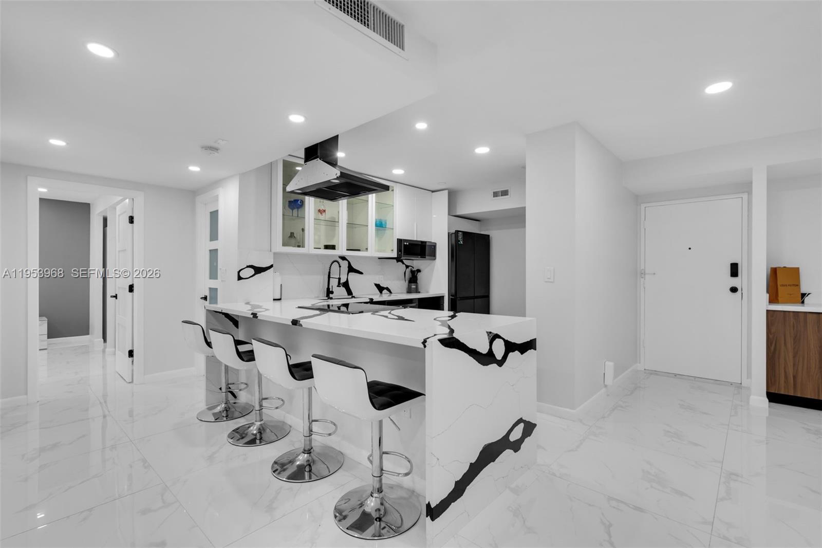 A modern kitchen features a white marble waterfall island with black veining and bar stools — 3800 Hillcrest Dr # 203, Hollywood FL 33021, HOLLYWOOD, FL