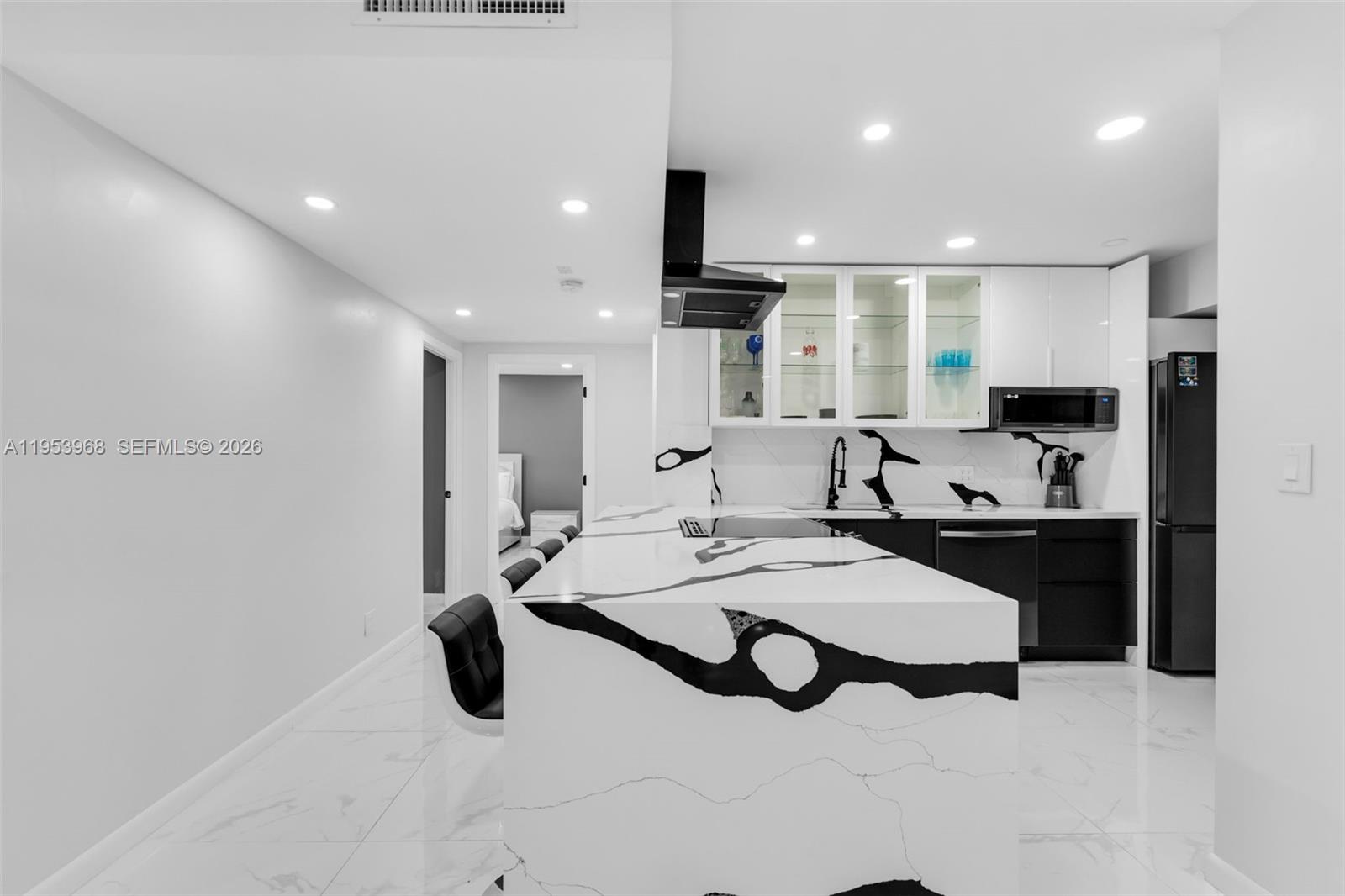A modern kitchen features a waterfall island with bold black veining and white cabinetry — 3800 Hillcrest Dr # 203, Hollywood FL 33021, HOLLYWOOD, FL