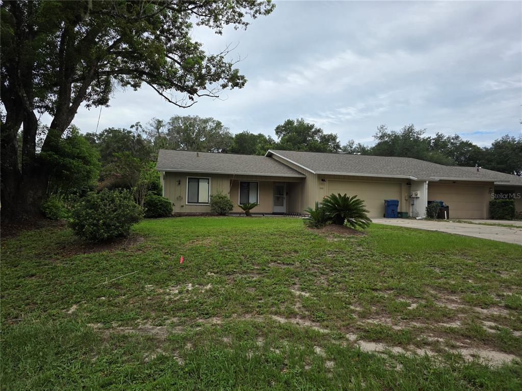 A single-story duplex with a tan exterior, attached garages, and a large front lawn — 1040 W VILLAGE GREEN ROAD, DELAND, FL