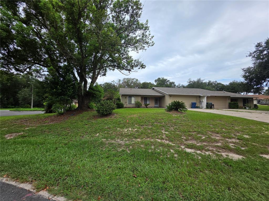 A single-story duplex with a tan exterior, a two-car garage, and a large front yard — 1040 W VILLAGE GREEN ROAD, DELAND, FL