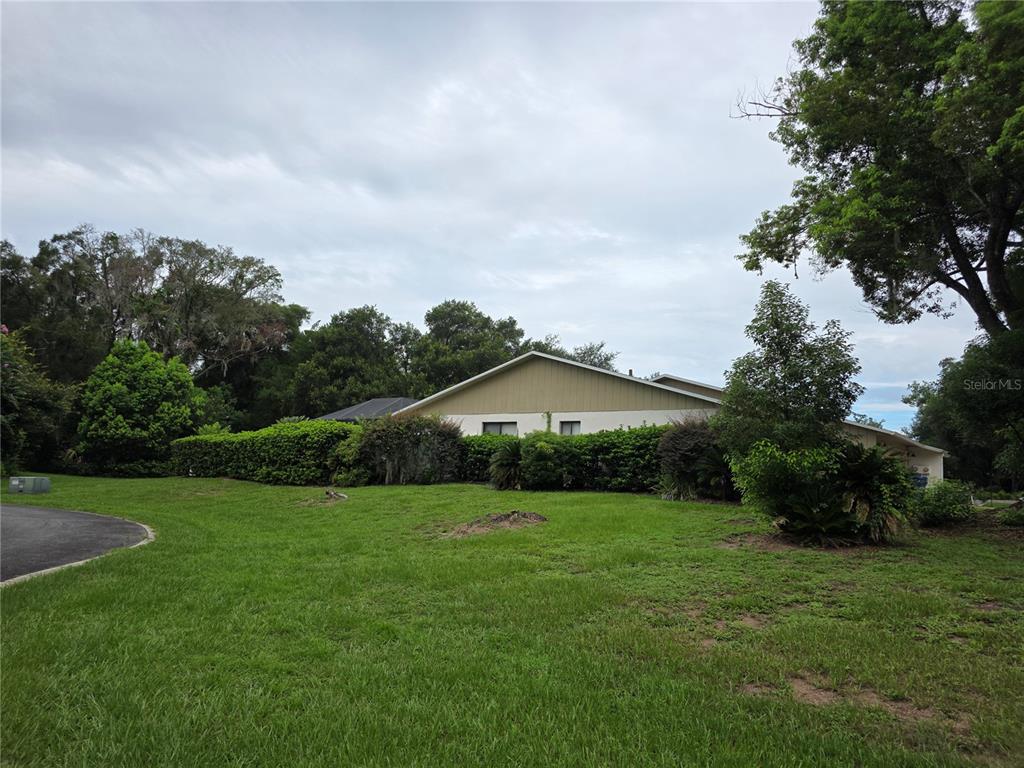 A view of a house exterior with a large lawn and surrounding trees — 1040 W VILLAGE GREEN ROAD, DELAND, FL