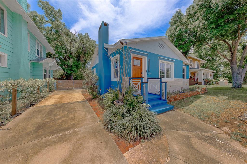 A blue house with a brick chimney and a concrete driveway sits on a lawn — 636 37TH AVENUE S, ST PETERSBURG, FL