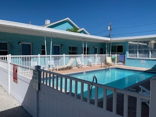 A turquoise motel building with a swimming pool enclosed by a white vinyl fence — 13343 GULF BOULEVARD UNIT A1, ST PETERSBURG, FL