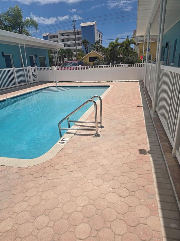 A bedroom features a kitchenette with white cabinets, a bed with blue patterned bedding, and a window — 13343 GULF BOULEVARD UNIT A1, ST PETERSBURG, FL