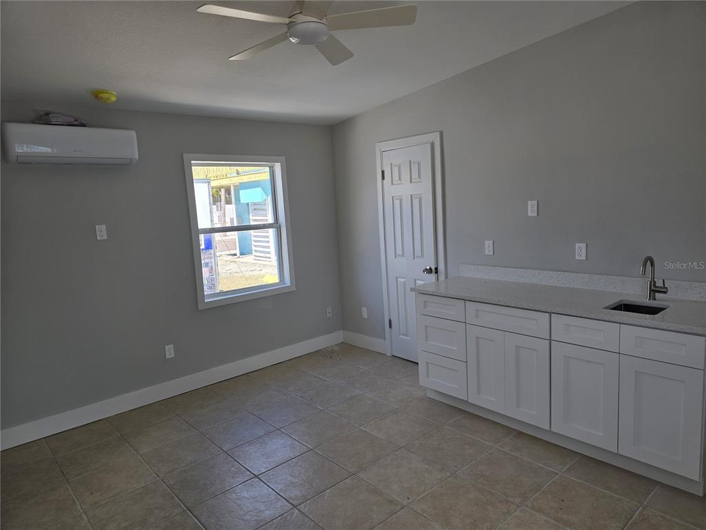 A bedroom features a bed, a kitchenette with white cabinets, and an attached bathroom — 13343 GULF BOULEVARD UNIT A1, ST PETERSBURG, FL