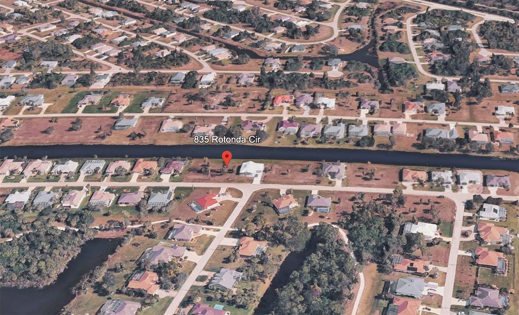 An aerial view shows a residential lot along a canal in a suburban neighborhood — 835 ROTONDA CIRCLE, ROTONDA WEST, FL