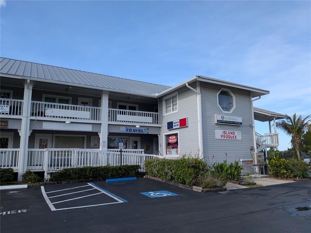 A two-story commercial building with gray siding, a metal roof, and a parking lot — 1120 PINELLAS BAYWAY S UNIT 211, ST PETERSBURG, FL