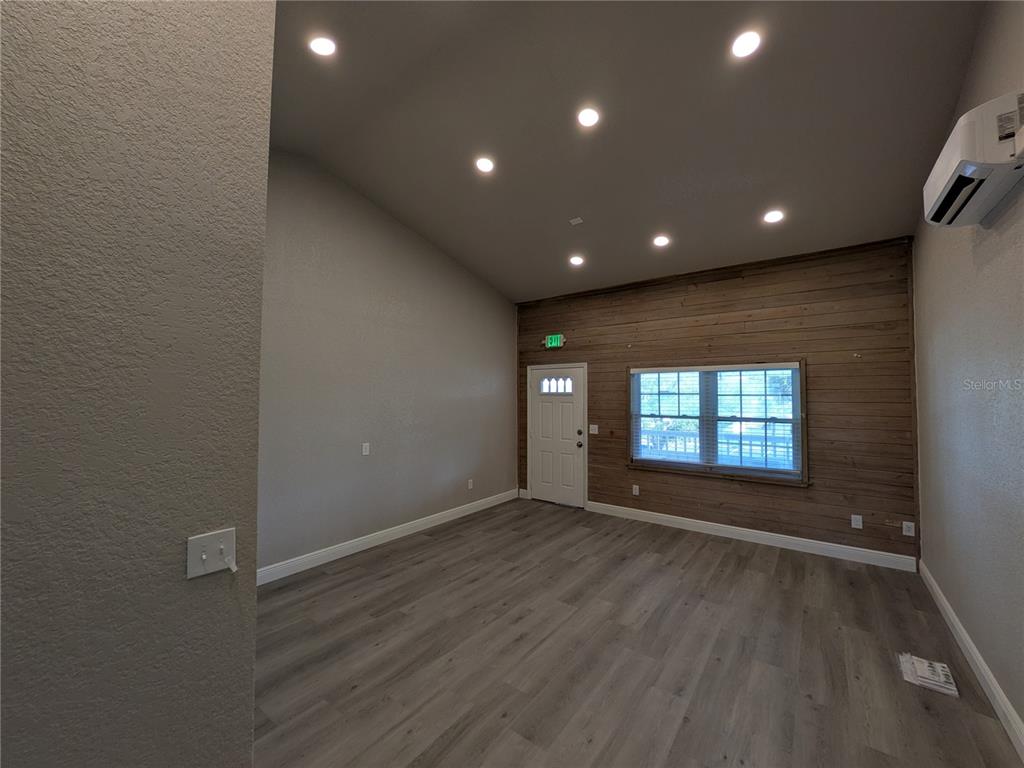 A room with gray wood-look flooring, recessed lighting, and a wood-paneled accent wall — 1120 PINELLAS BAYWAY S UNIT 211, ST PETERSBURG, FL
