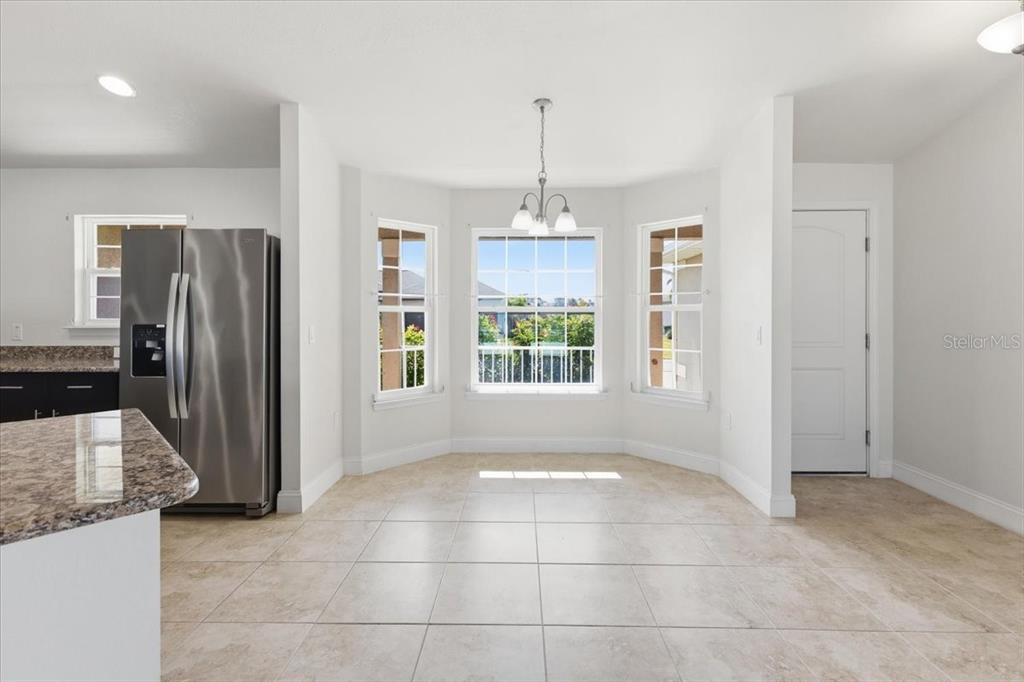A bright dining nook features tile flooring, a bay window, and a modern pendant light — 191 W PINE VALLEY LANE, ROTONDA WEST, FL