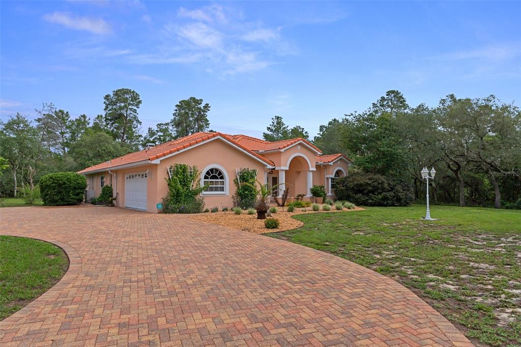 A peach-colored house with a red tile roof and a brick paver driveway — 4525 W ALAMO DRIVE, BEVERLY HILLS, FL
