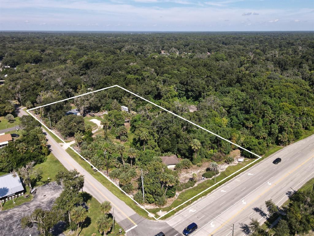 An aerial view shows a wooded lot outlined in white situated between two roads — 235 W WISCONSIN AVENUE, ORANGE CITY, FL