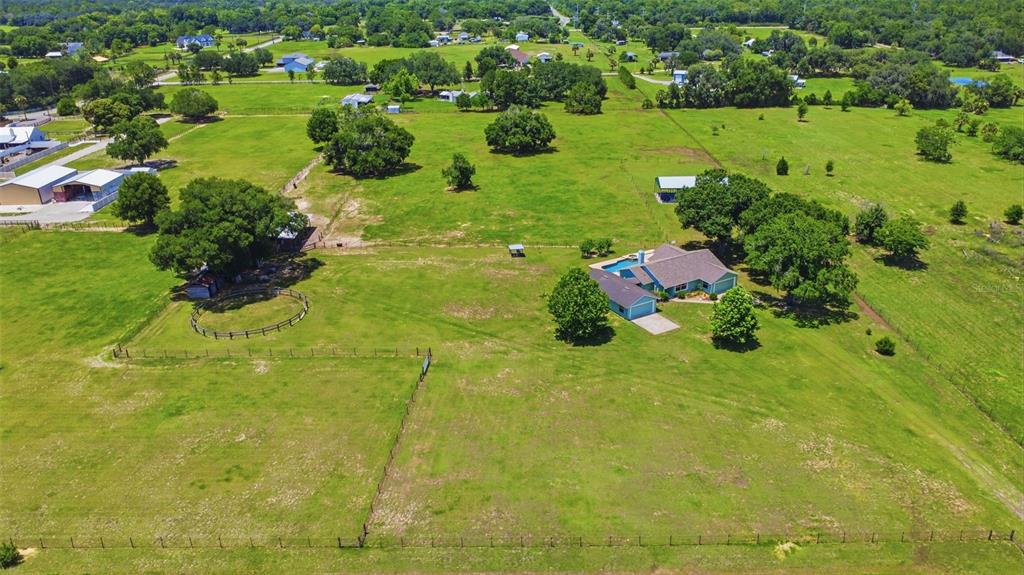 An aerial view shows a house with a pool and a fenced pasture with trees — 1200 N HART ROAD, GENEVA, FL