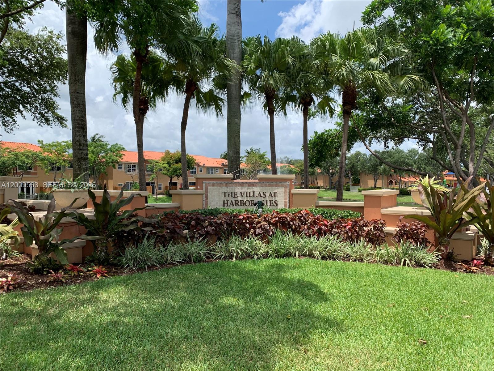 The entrance sign for The Villas at Harbor Isles stands before palm trees and buildings — 4944 Windward Way # 1401, Dania Beach FL 33312, DANIA BEACH, FL