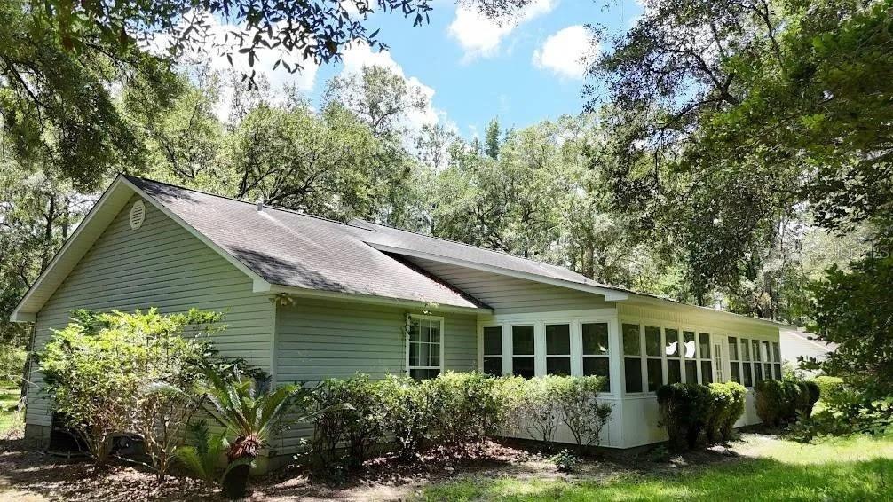A light-colored house with a screened-in porch surrounded by trees and landscaping — 6794 STURMER PLACE, TALLAHASSEE, FL