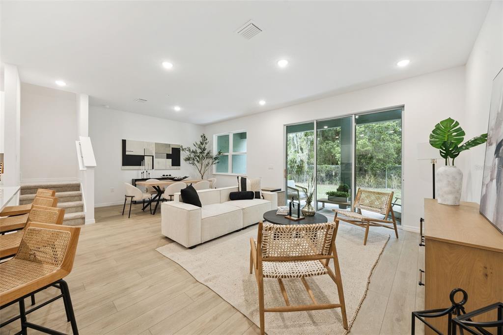 A bright, open-concept living and dining area features light wood flooring and sliding glass doors — 5204 LUISA COURT, ST CLOUD, FL