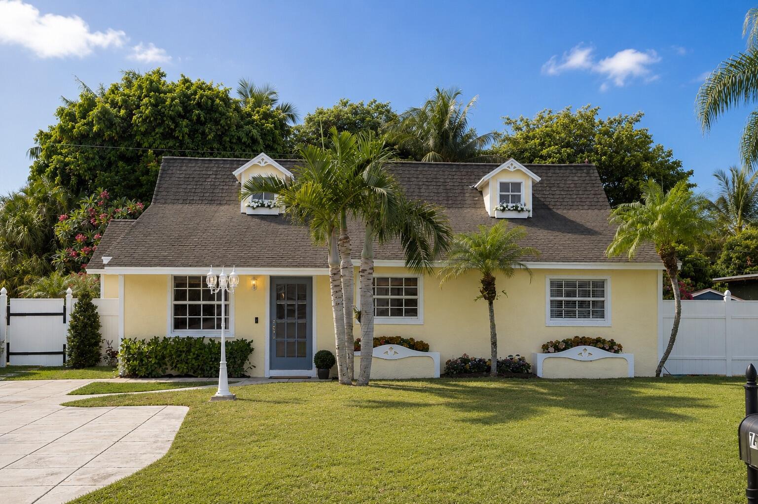 A yellow cottage-style house with a gray roof, dormer windows, and palm trees in front — 7416 Overlook Drive, Lake Worth FL 33467, LAKE WORTH, FL