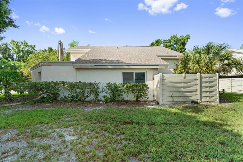 The exterior of a single-story home features a tan stucco wall, a shingled roof, and landscaping — 2630 CEDAR VIEW COURT UNIT 0, CLEARWATER, FL