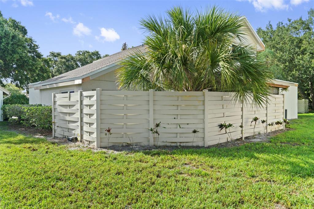A beige horizontal-slat privacy fence stands in front of a house with a palm tree — 2630 CEDAR VIEW COURT UNIT 0, CLEARWATER, FL