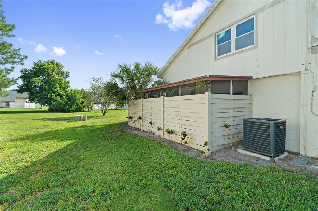 The exterior of a house features a screened-in patio, a privacy fence, and an air conditioner — 2630 CEDAR VIEW COURT UNIT 0, CLEARWATER, FL