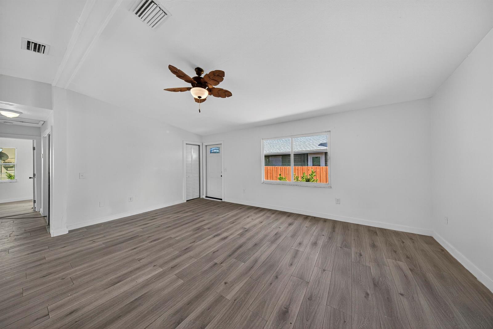 An empty room features white walls, wood-look laminate flooring, a ceiling fan, and a window — 117 NE 8th Street, Pompano Beach FL 33060, POMPANO BEACH, FL