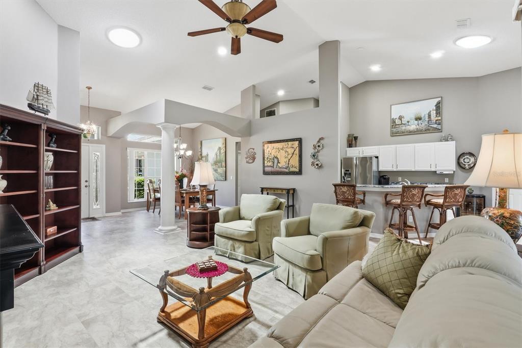 A spacious living room with tile floors, a ceiling fan, and an open kitchen area — 6042 LANDINGS BOULEVARD, LADY LAKE, FL