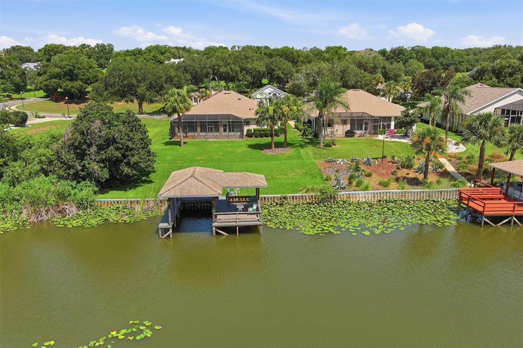 An aerial view of two houses with screened lanais, a boat dock, and a lake — 6042 LANDINGS BOULEVARD, LADY LAKE, FL