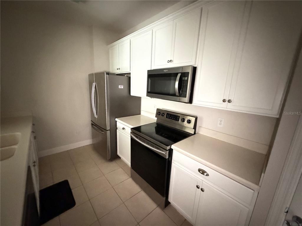 A kitchen with white cabinets, stainless steel appliances, and light-colored tile flooring — 3326 ROBERT TRENT JONES DRIVE UNIT 10502, ORLANDO, FL