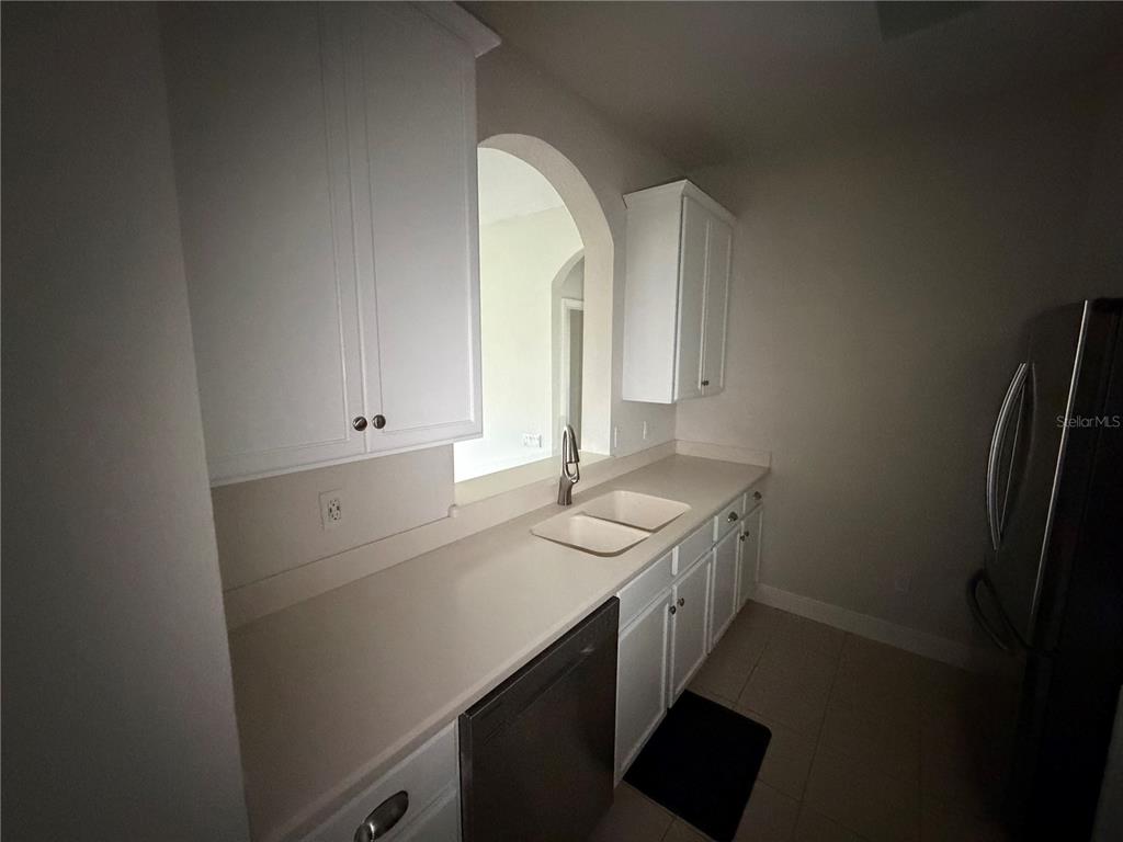 A kitchen features white cabinets, light countertops, a double sink, and stainless steel appliances — 3326 ROBERT TRENT JONES DRIVE UNIT 10502, ORLANDO, FL